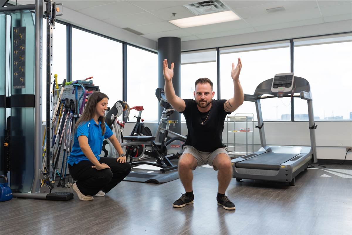 A physiotherapist coaching a patient through a squat