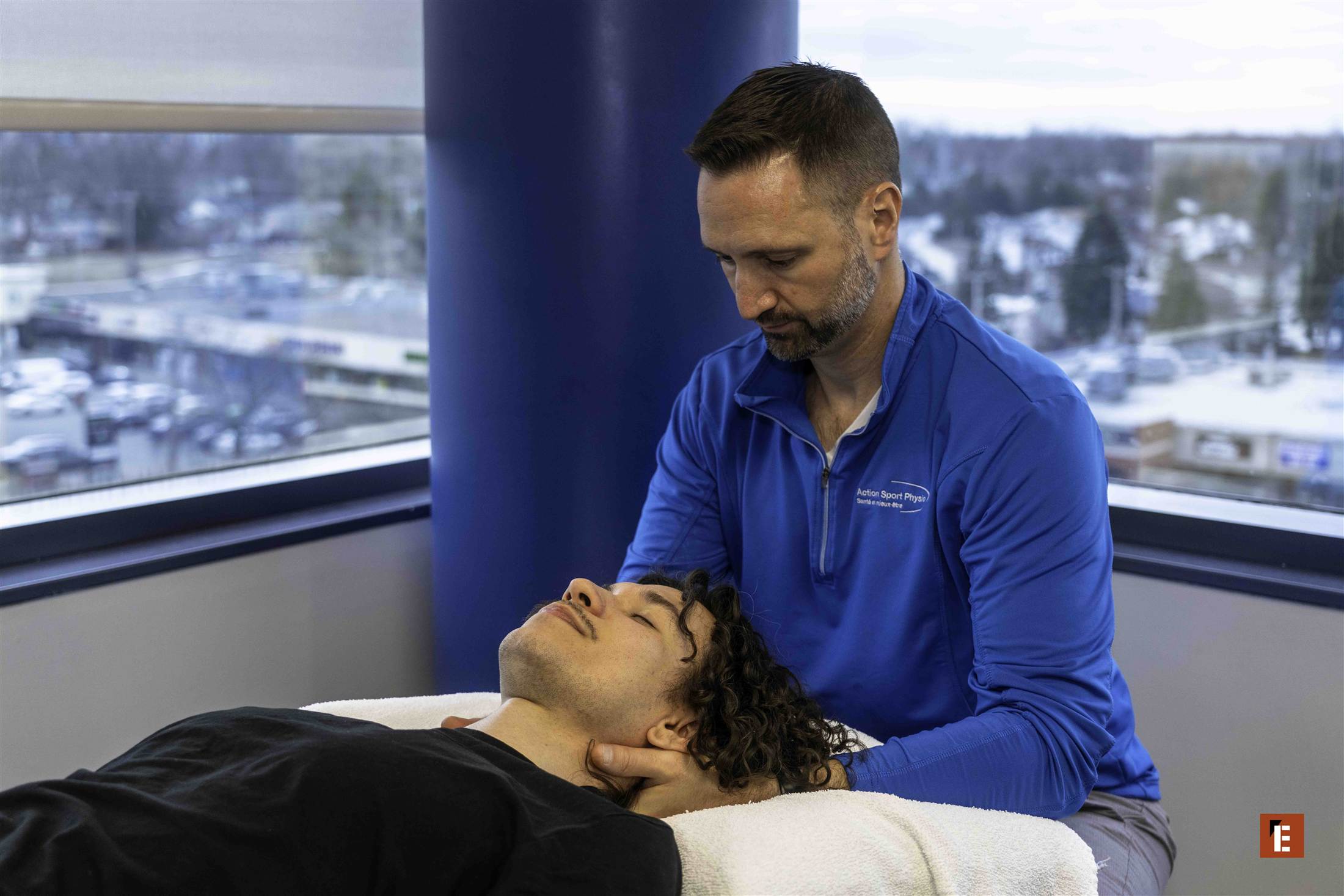 A physiotherapist treating a patient's neck by the window